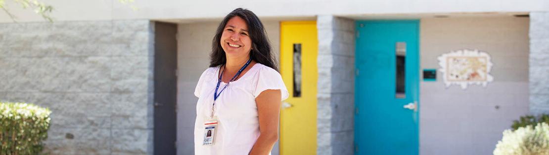 A Faculty Memebt Stands smiling in front of one of Pima's Adult Learning Center